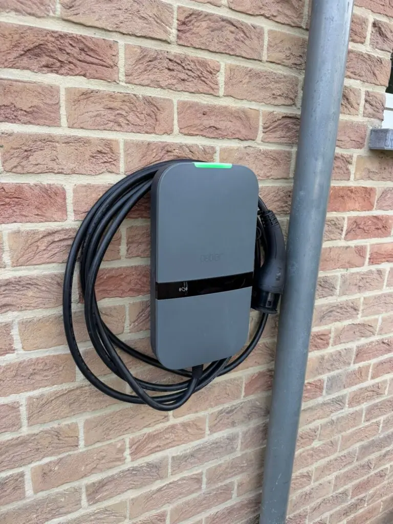 Laadpaal aan een gevel met opgerolde kabel, geplaatst door Electrifusion