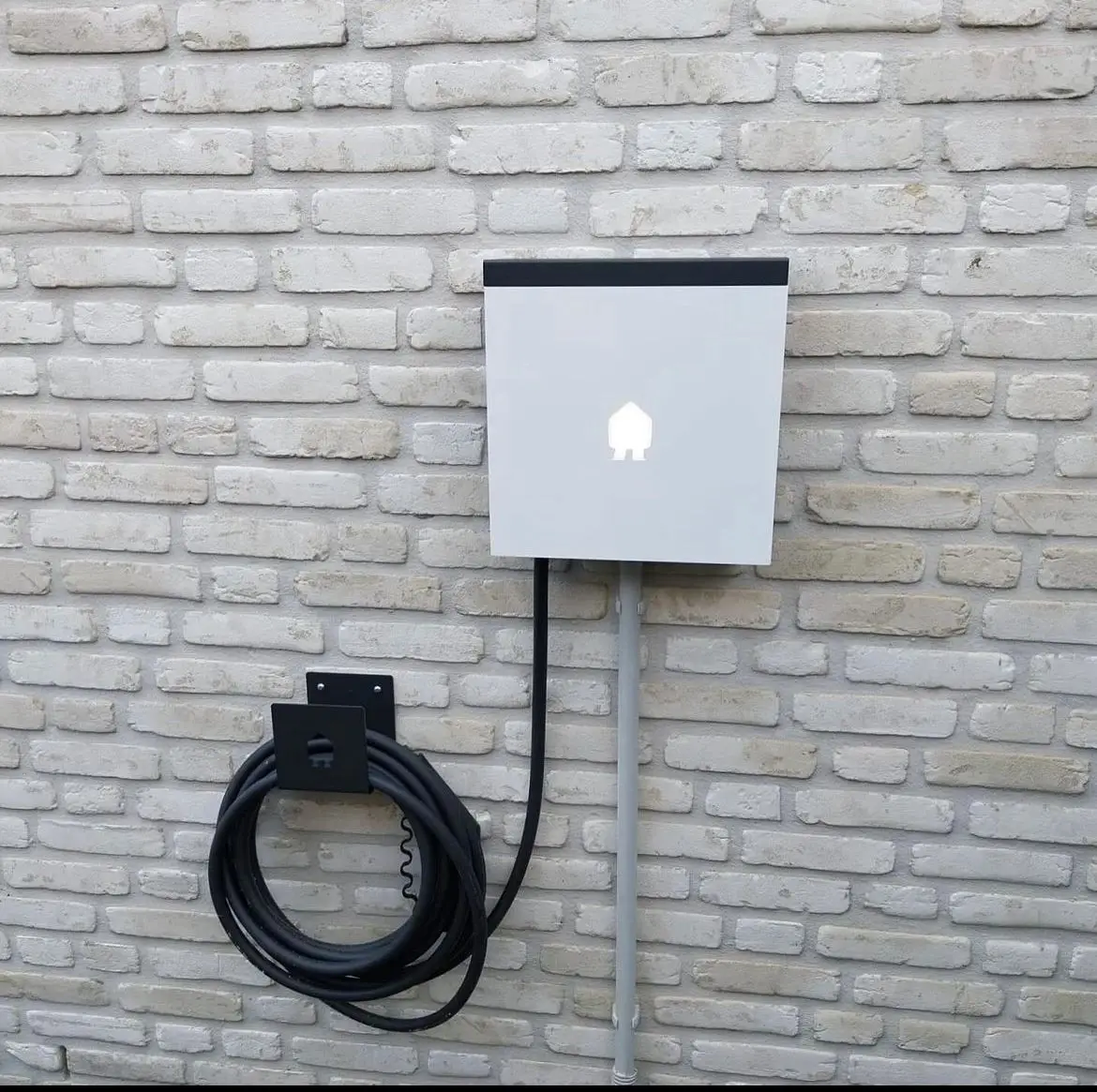 Laadpunt met aparte kabelhouder aan een lichte gevel, geplaatst door Electrifusion